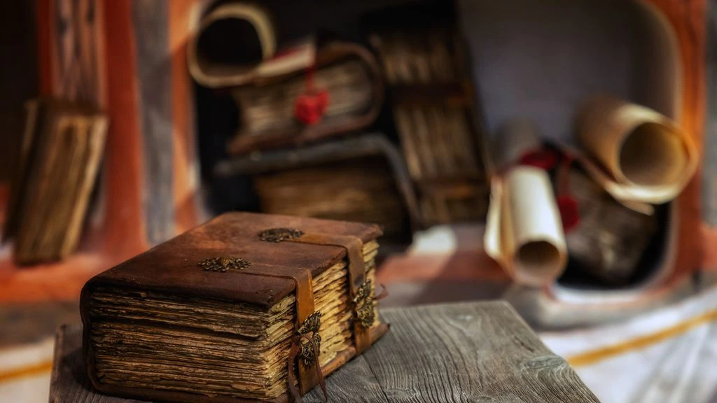 A leather-bound journal and reading glasses on a wooden table.