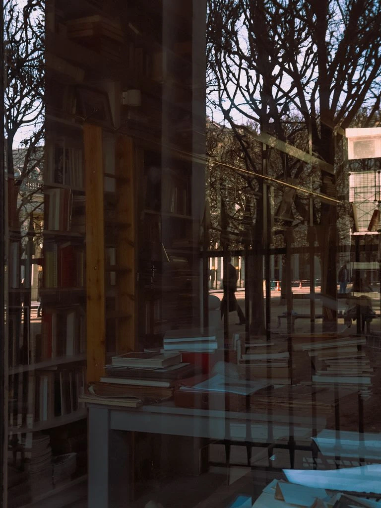 An empty library reading room at dusk with long wooden tables and brass lamps.