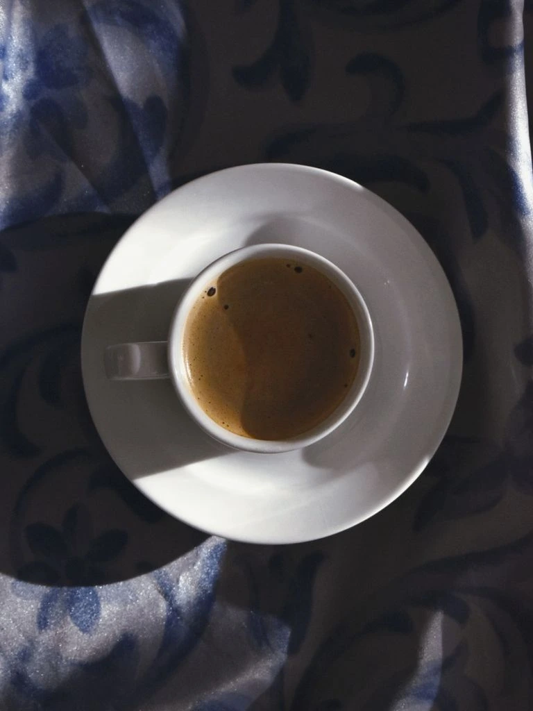 A ceramic coffee cup beside a small stack of well-worn paperbacks in soft window light.